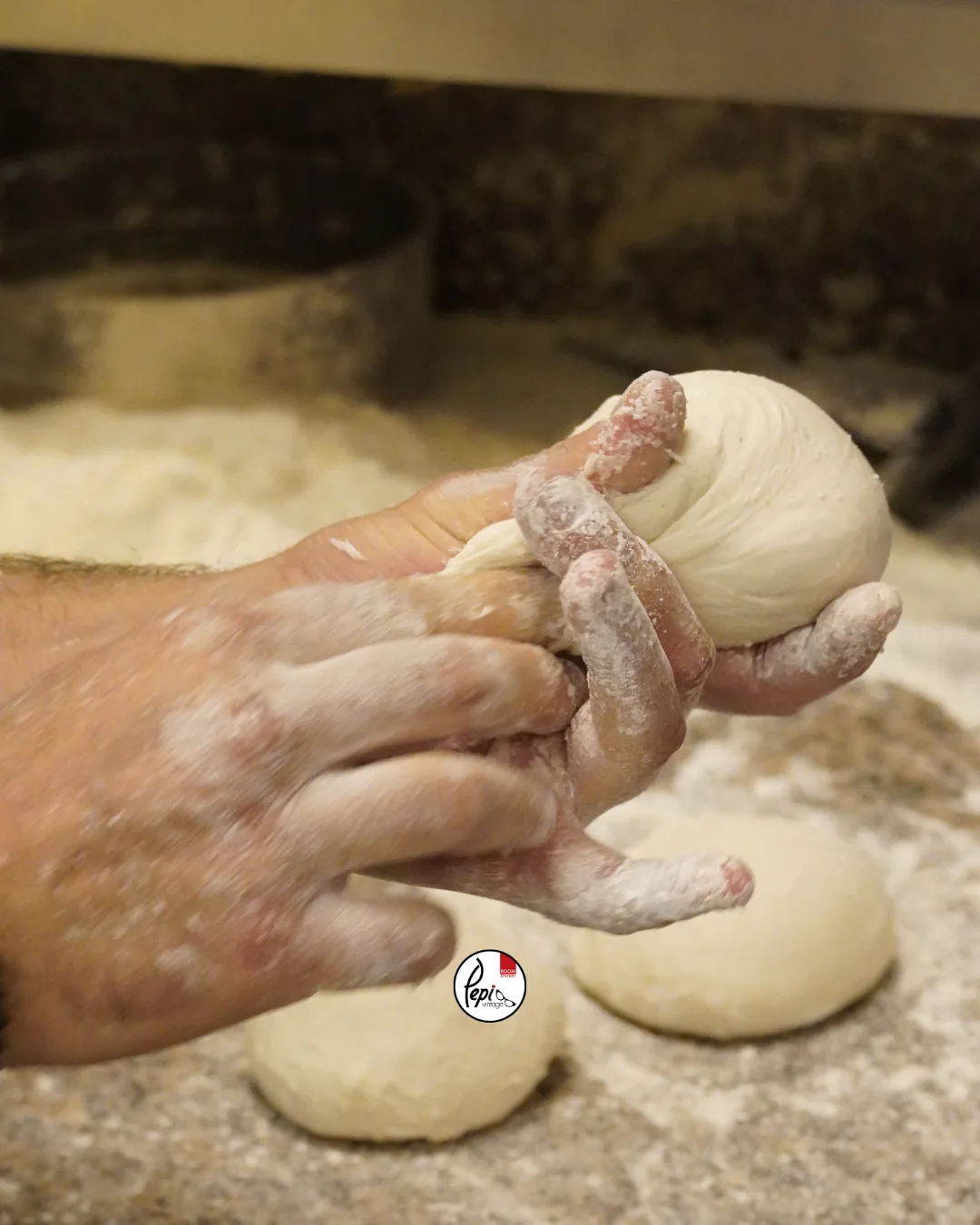 Hands working pizza dough in the prep room