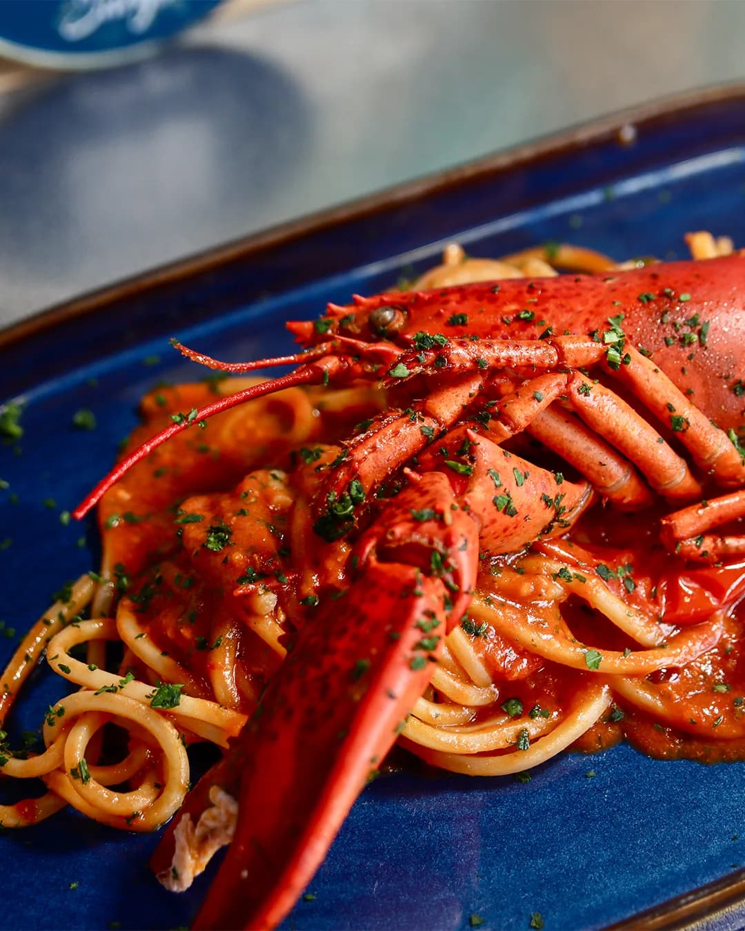 Lobster spaghetti served on a blue plate, photographed at the restaurant